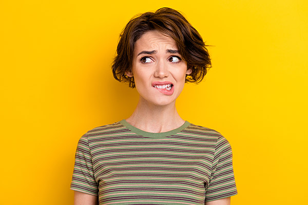 Eine junge Frau schaut &auml;ngstlich und bei&szlig;t sich auf die Lippen.